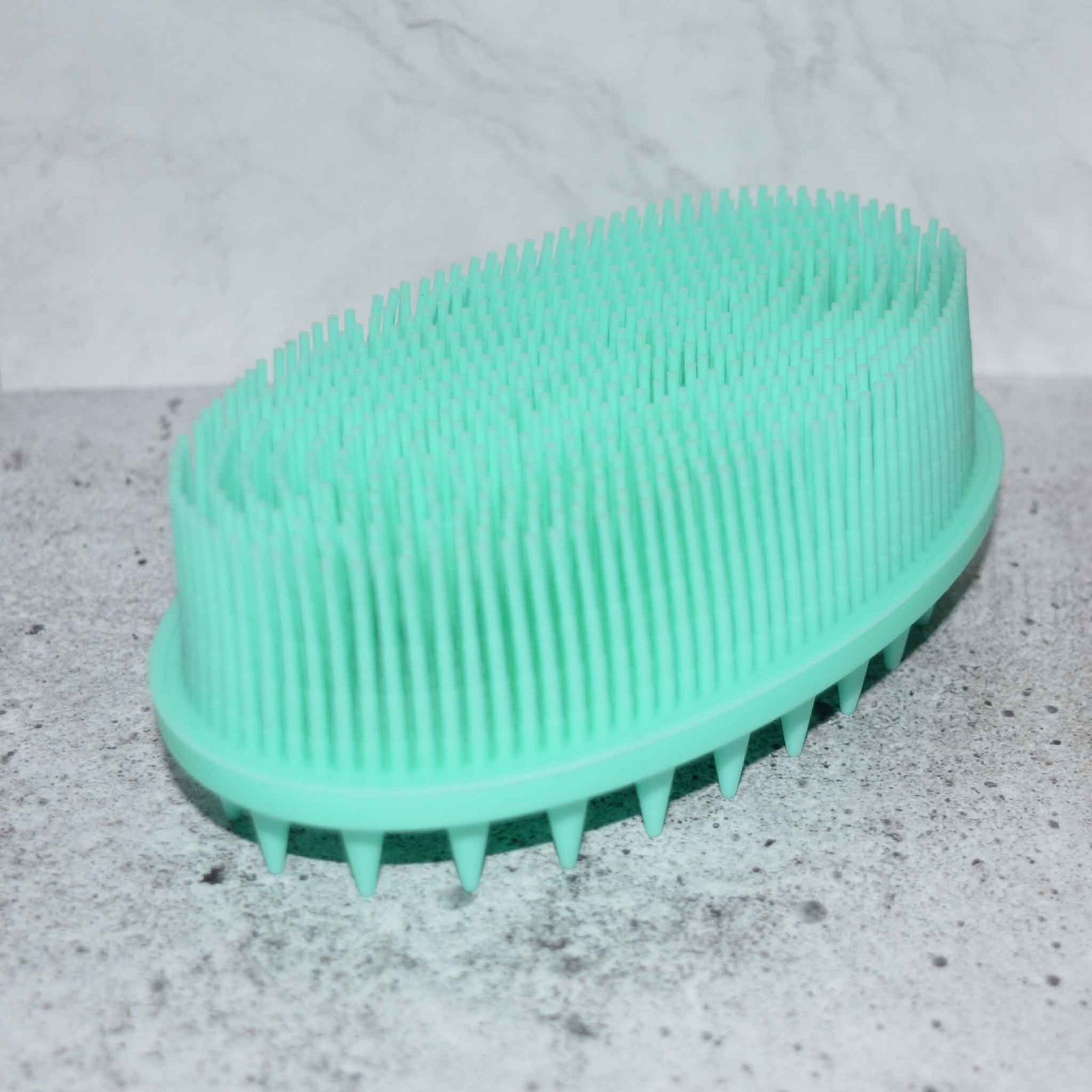 Pink soft silicone scrub brush with very soft fine bristles on one side, and short firm nubs on the other side