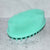 Pink soft silicone scrub brush with very soft fine bristles on one side, and short firm nubs on the other side