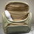 A green handbag style toiletry bag with duel zips for the main section, a side pouch and a gold tag with the showalux logo on a gold chain, on a marble top