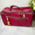 Pink travel bag with gold zippers on a marble surface with flowers in the background