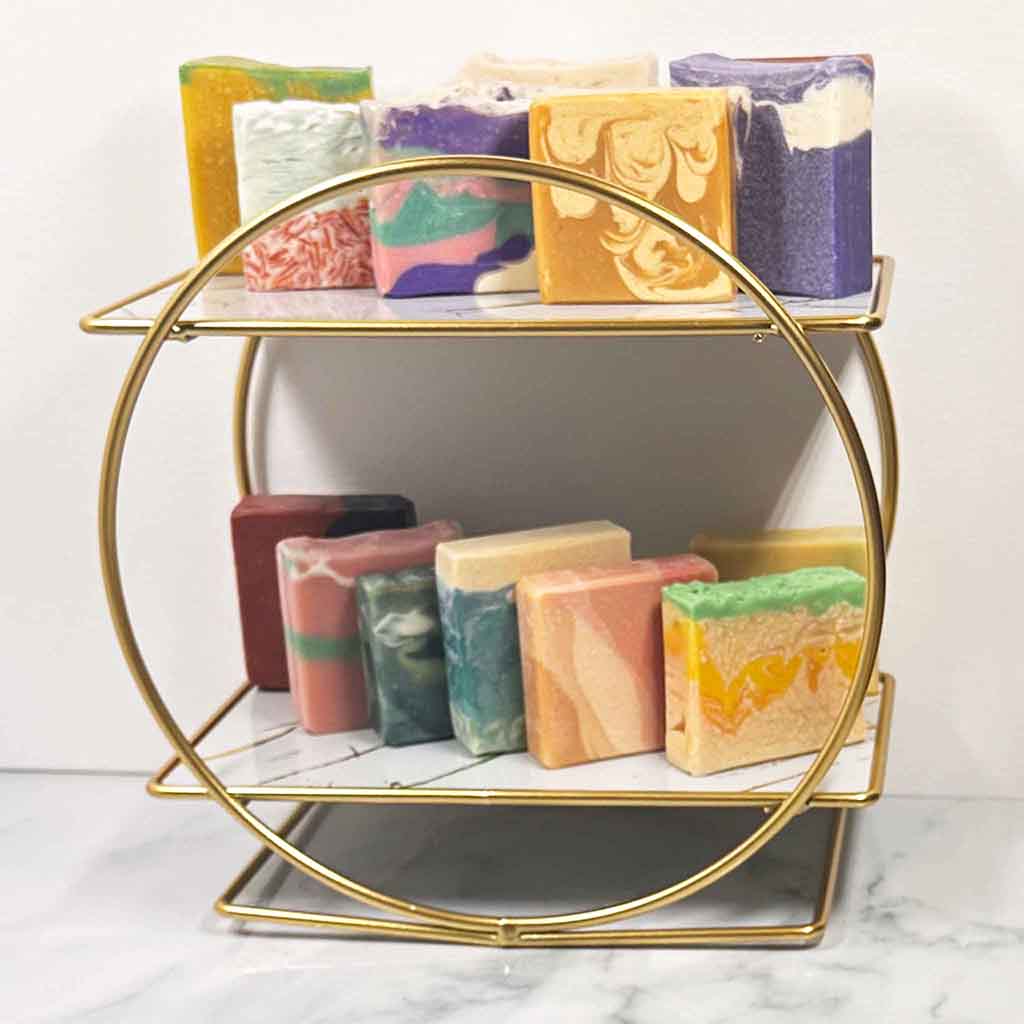 Gold tiered soap holder with luxury Showalux soap bars on a marble surface.