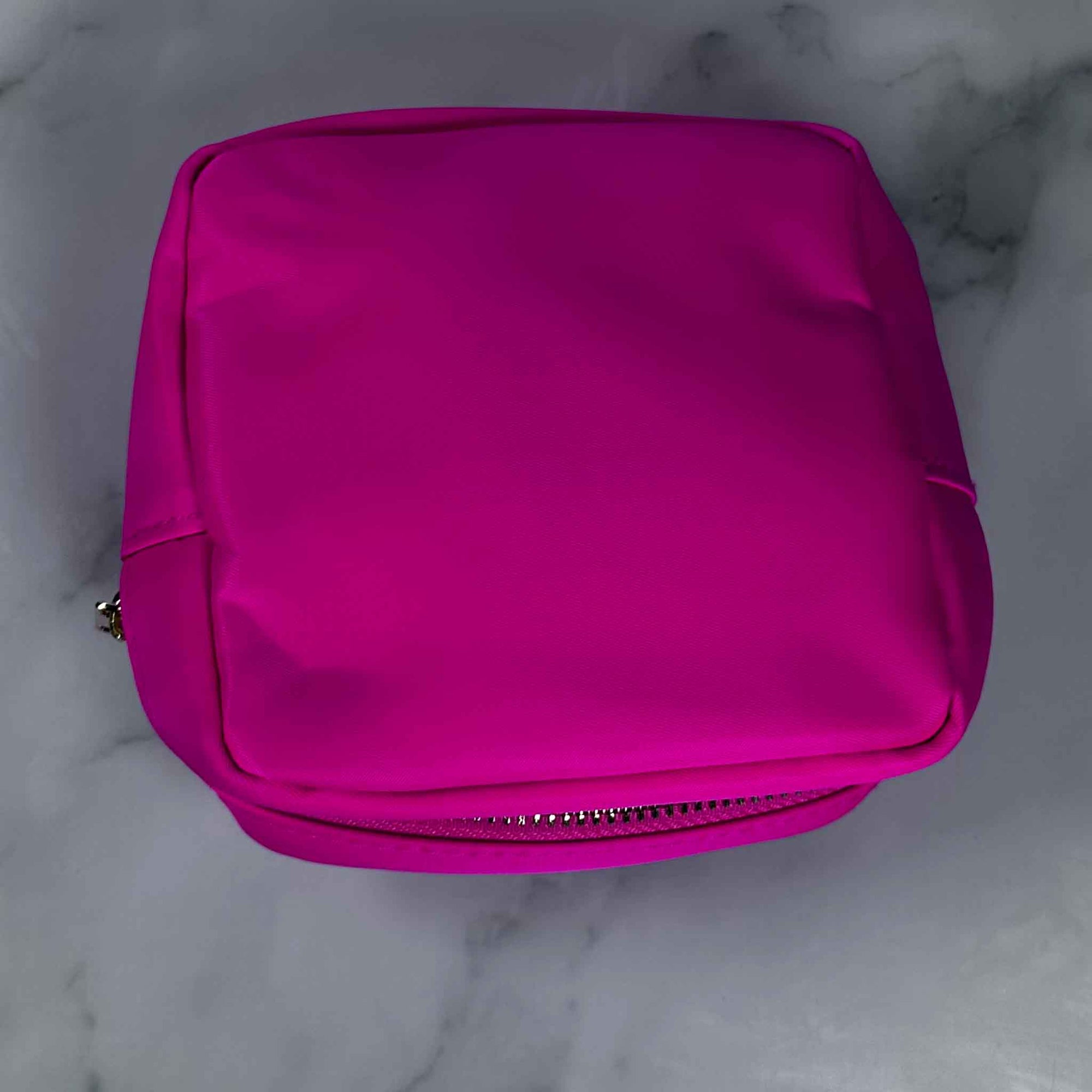 Hot Pink Showalux personal bag with a zipper on a marble surface