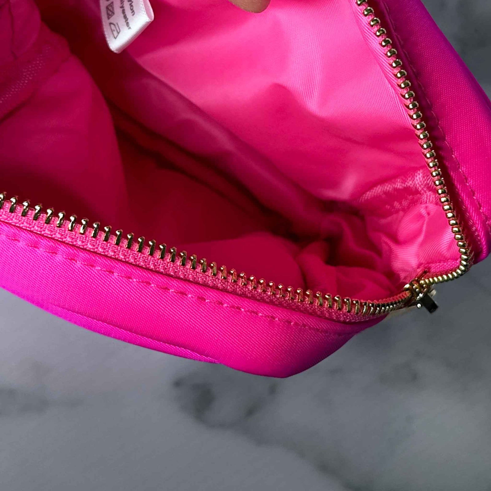 Close-up of a pink bag with lining and a gold zipper on a gray background