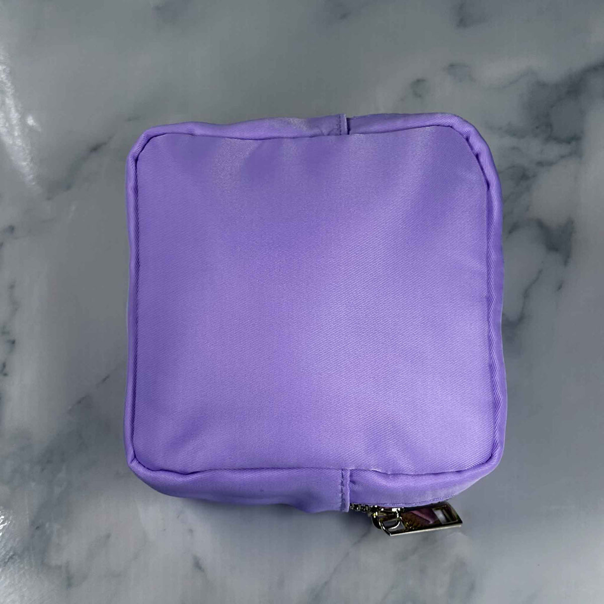 Purple Showalux personal bag with a gold zipper on a marble surface