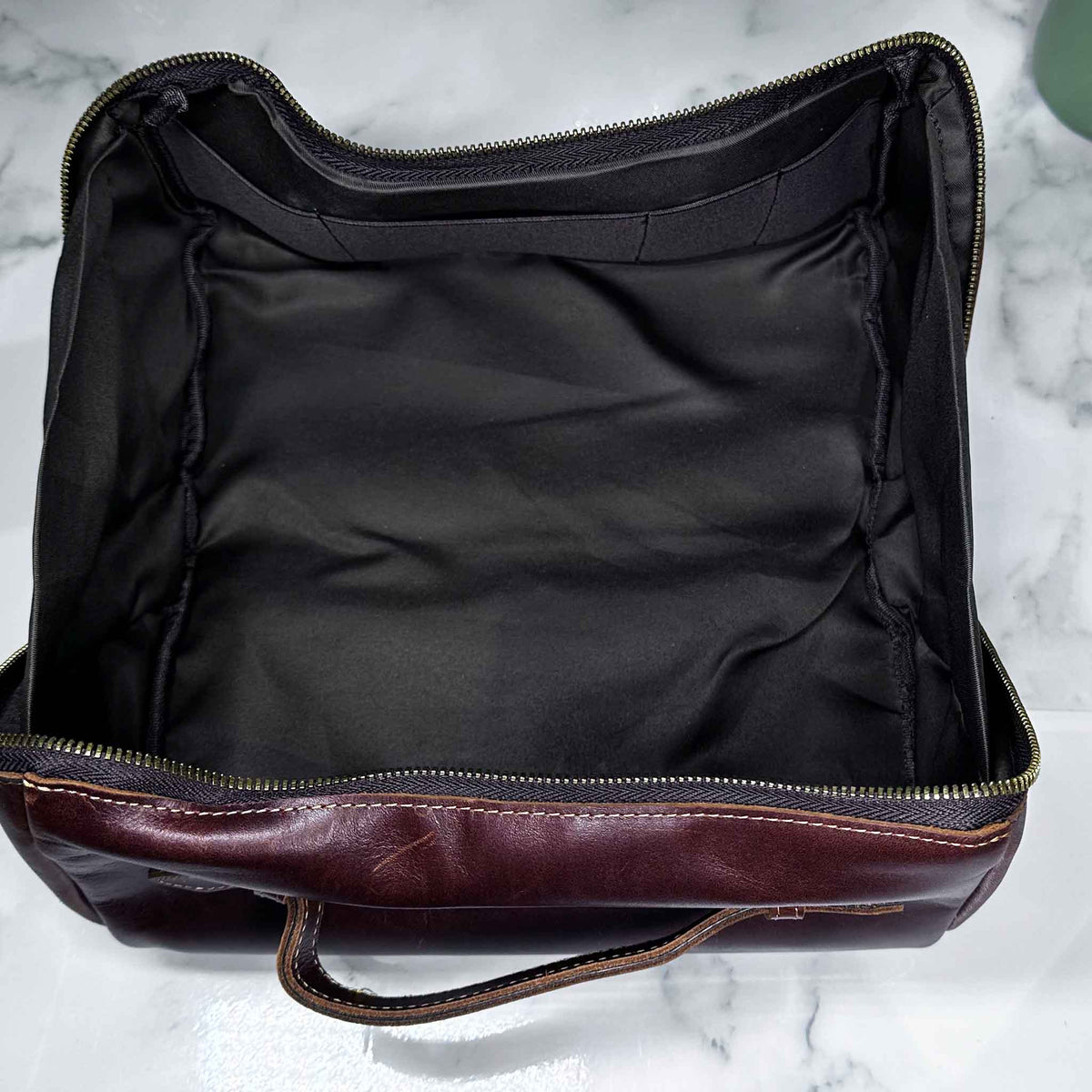 Black leather bag with brown leather handle on a marble surface