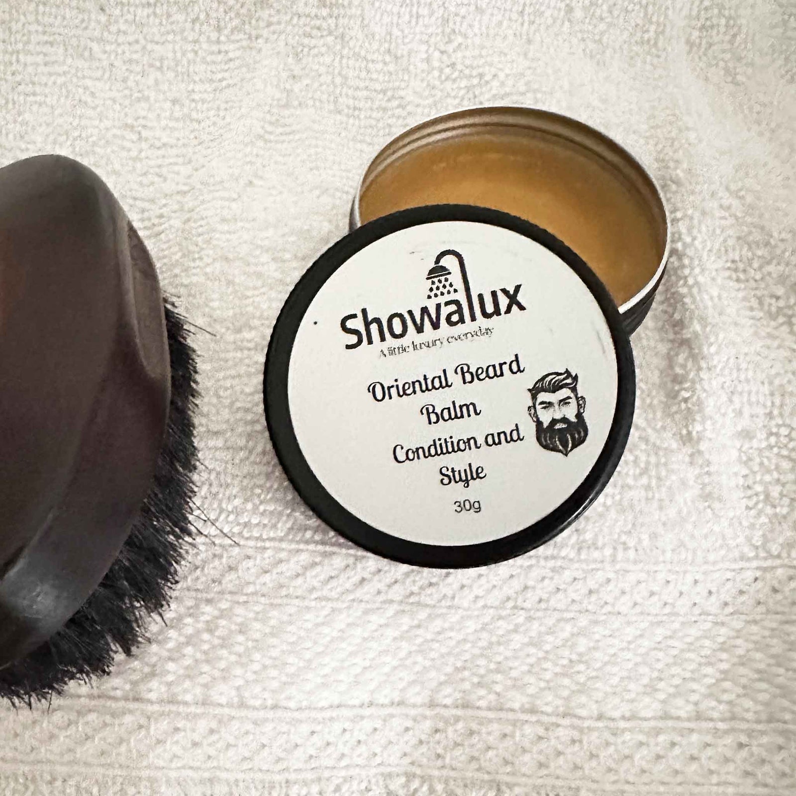 Showalux Oriental Beard Balm container with a brush on a textured white background