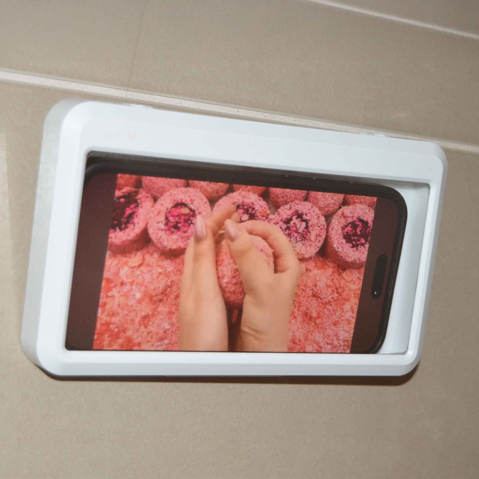 White Phone holder on tiled wall with phone inside showing bright pink pictures