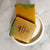 A square cake of soap yellow and a green top on a marble background
