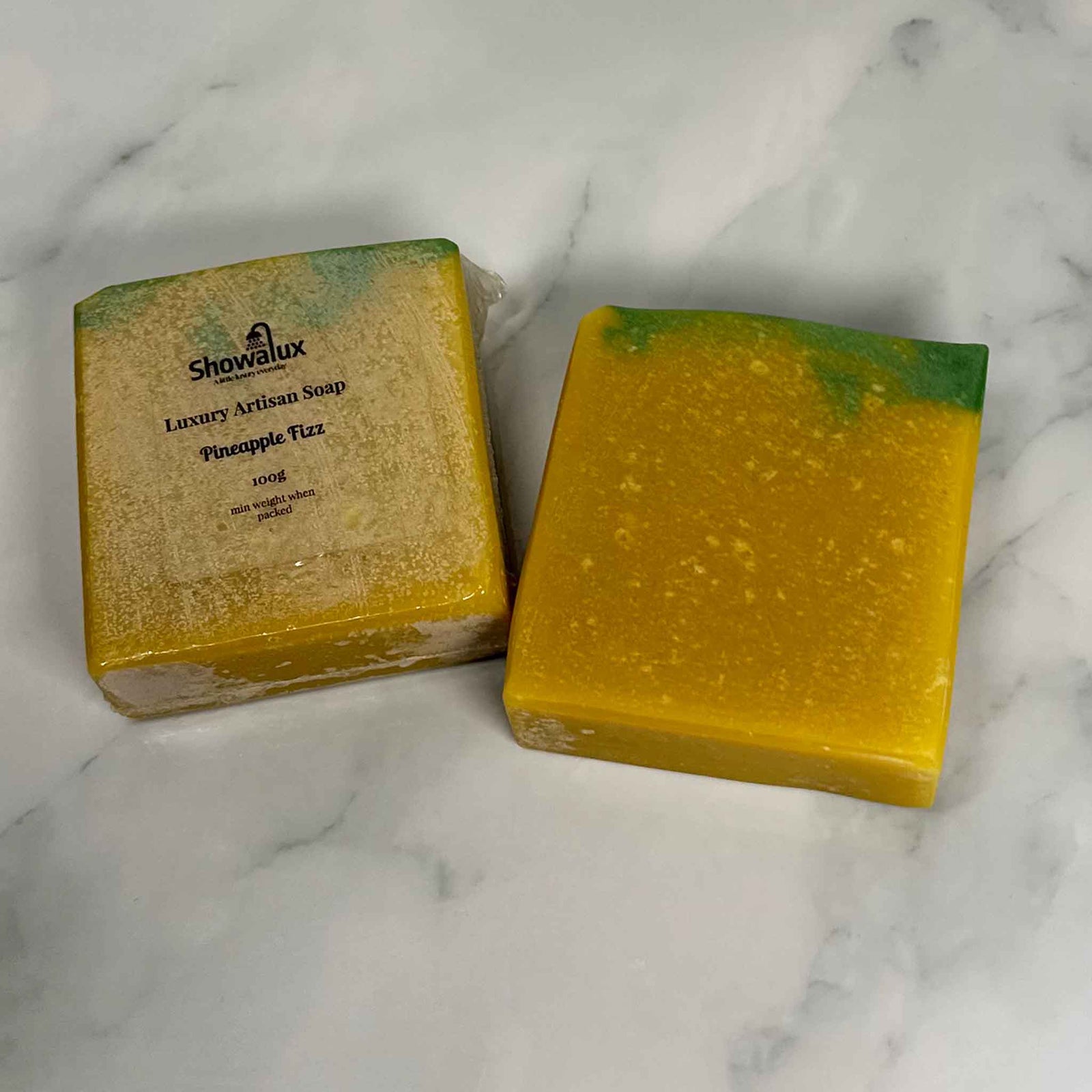 A square cake of soap yellow and a green top on a marble background