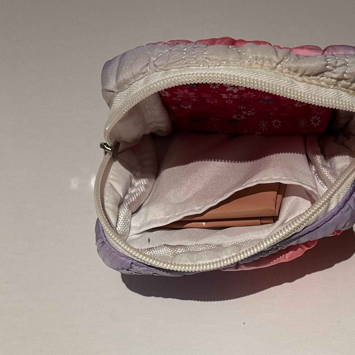 A small square bag, open and showing inside pocket