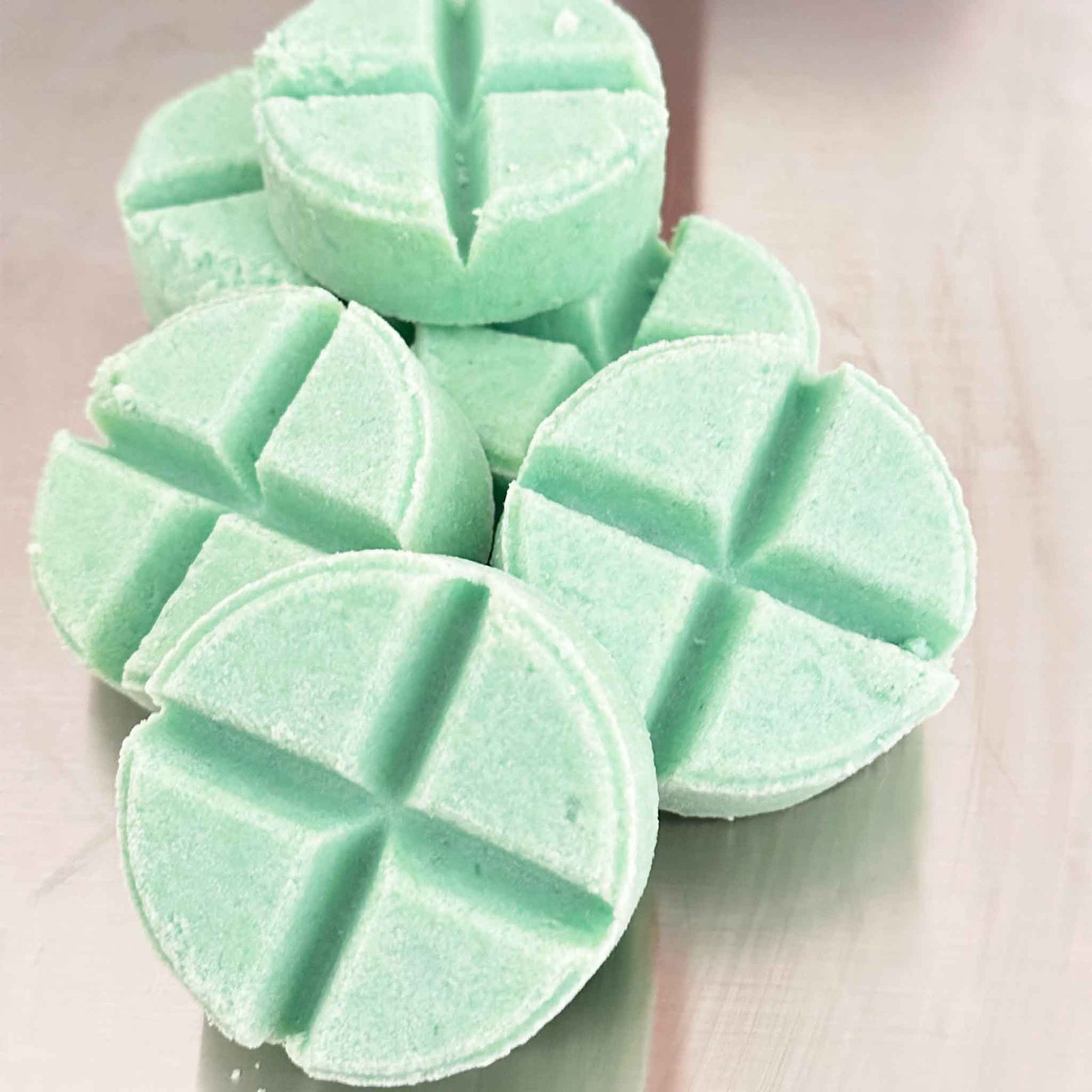 Green Showalux shower steamer with a ribbon on a metallic surface