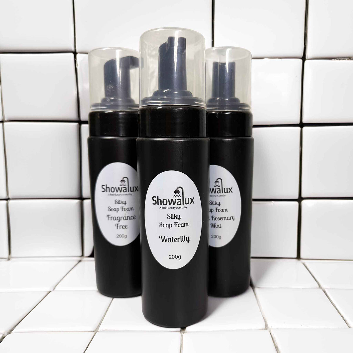 Three Showalux soap foam bottles on a tiled bathroom floor.
