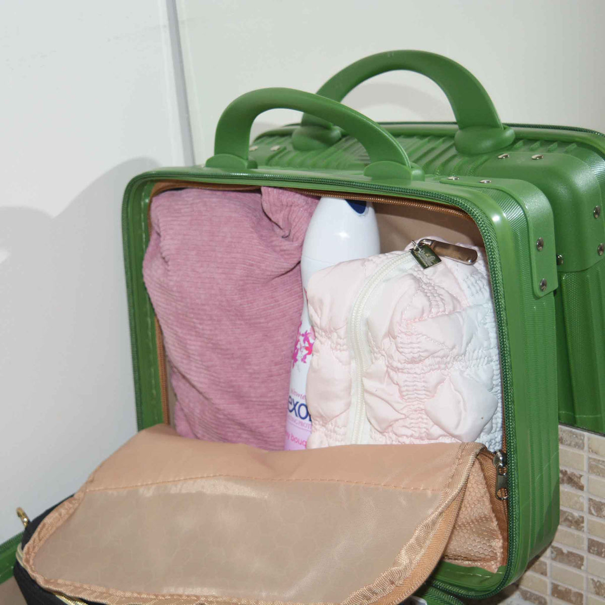 Green suitcase style bag showing the lid side behind the zipped fabric enclosure