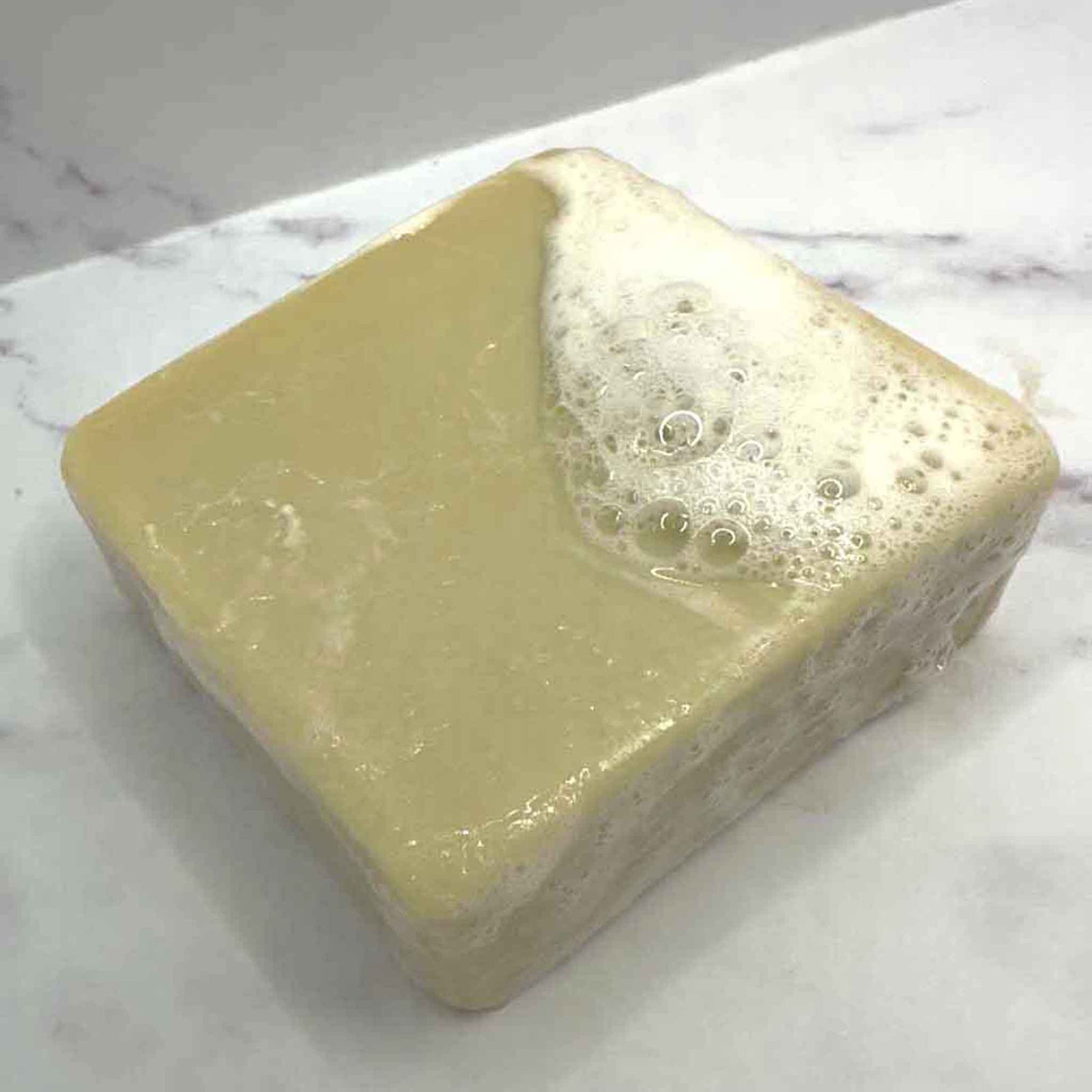 2 Plain green tinged soap bars on a stone background