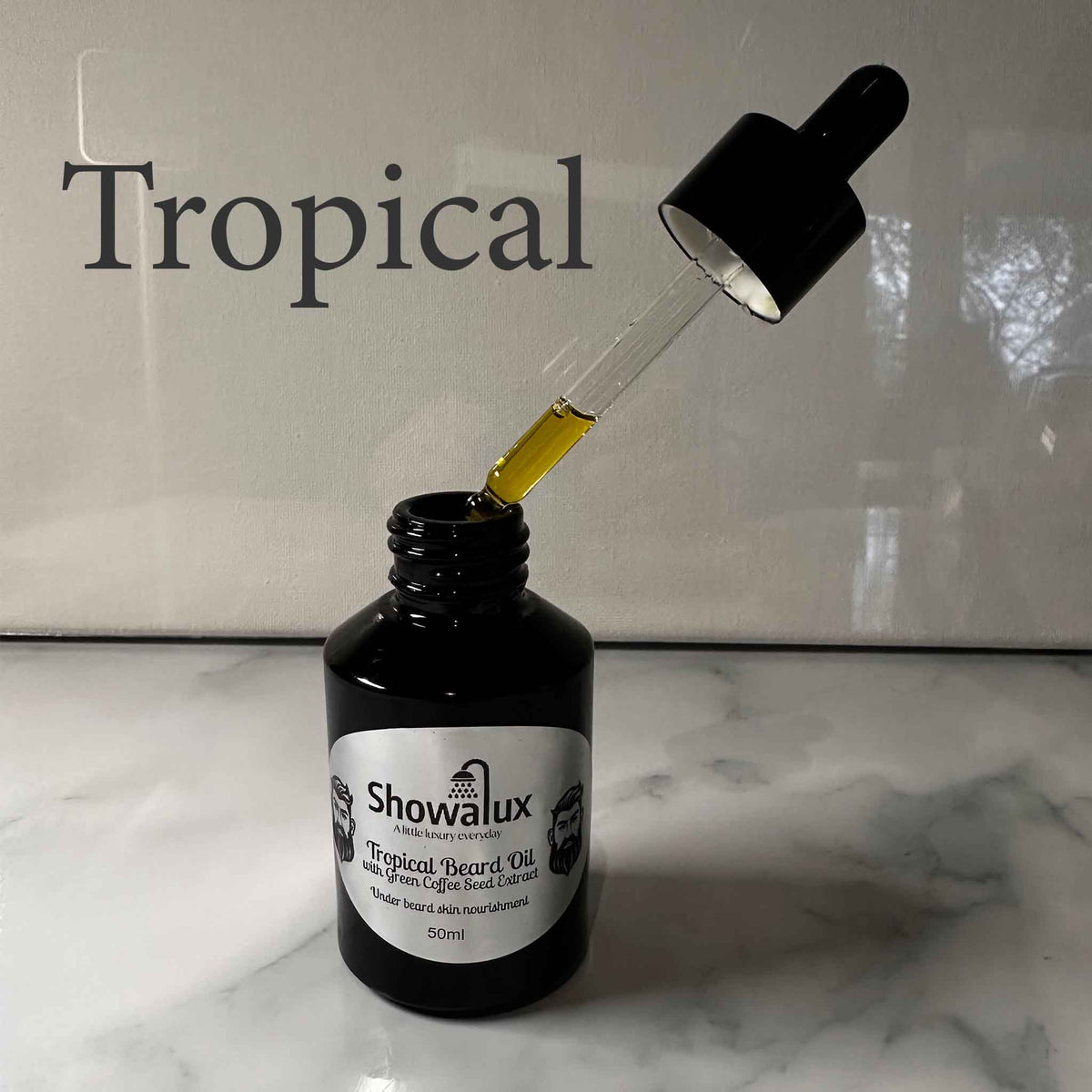 A small bottle of beard oil with a silver label and an eye dropper, dripping oil into the bottle fragrance is Tropical