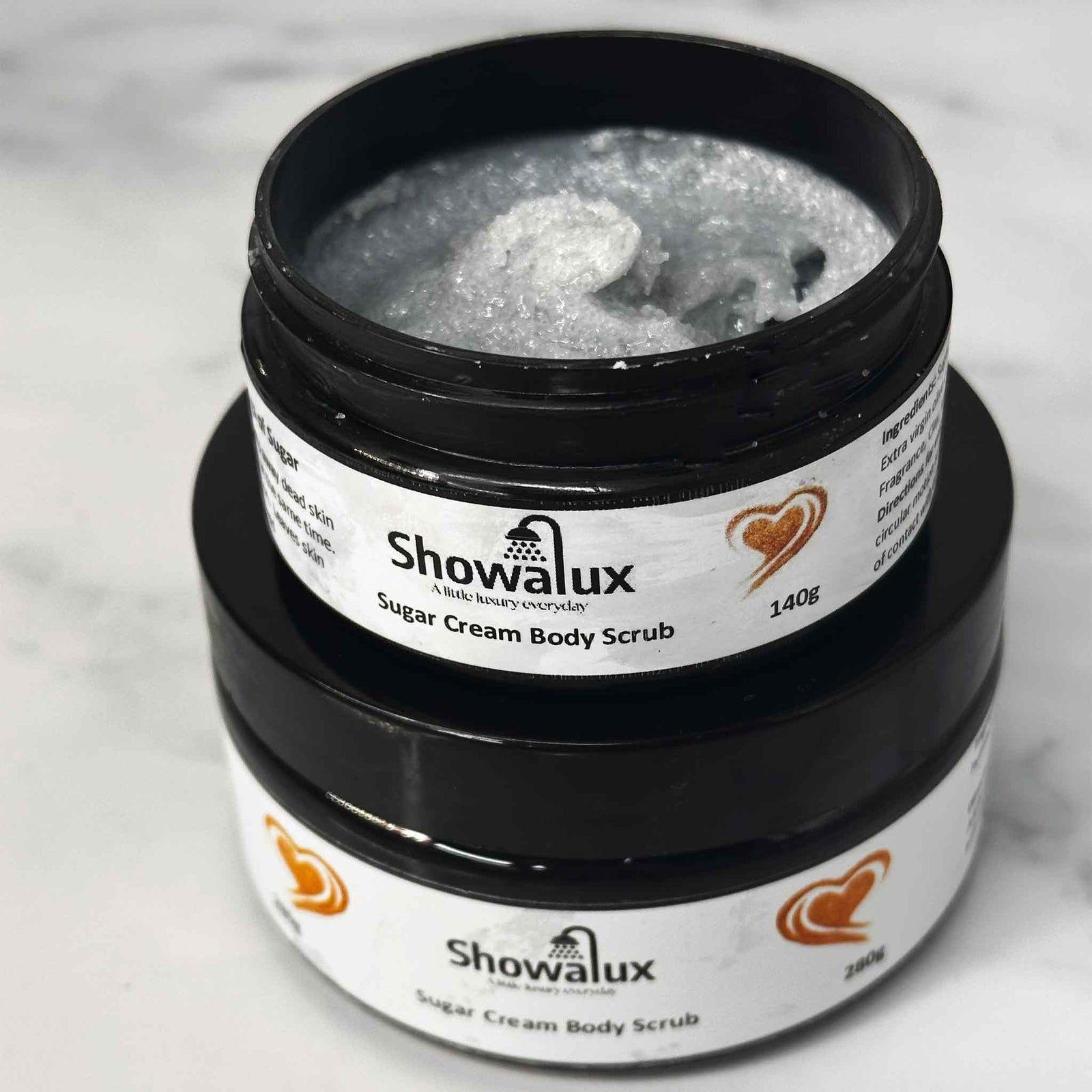Showalux sugar cream body scrub small and large jar on a marble surface