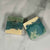 2 soap bars coloured blue, green and cream, one with a label,  on a marble background