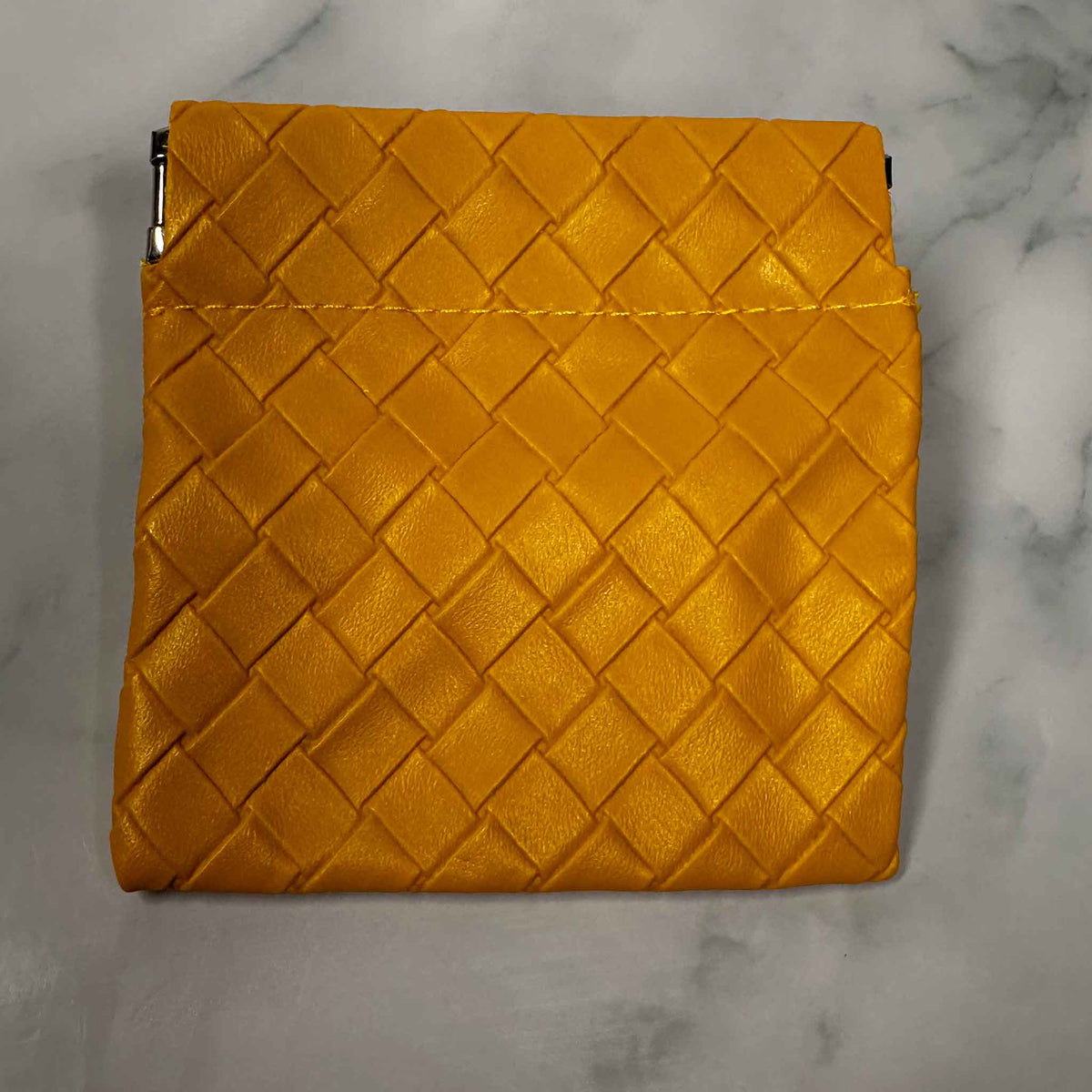 Gold woven personal Showalux bag on a marble surface