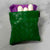 Green woven Showalux personal bag showing contents of  purple panty liners and tampons on a marble surface