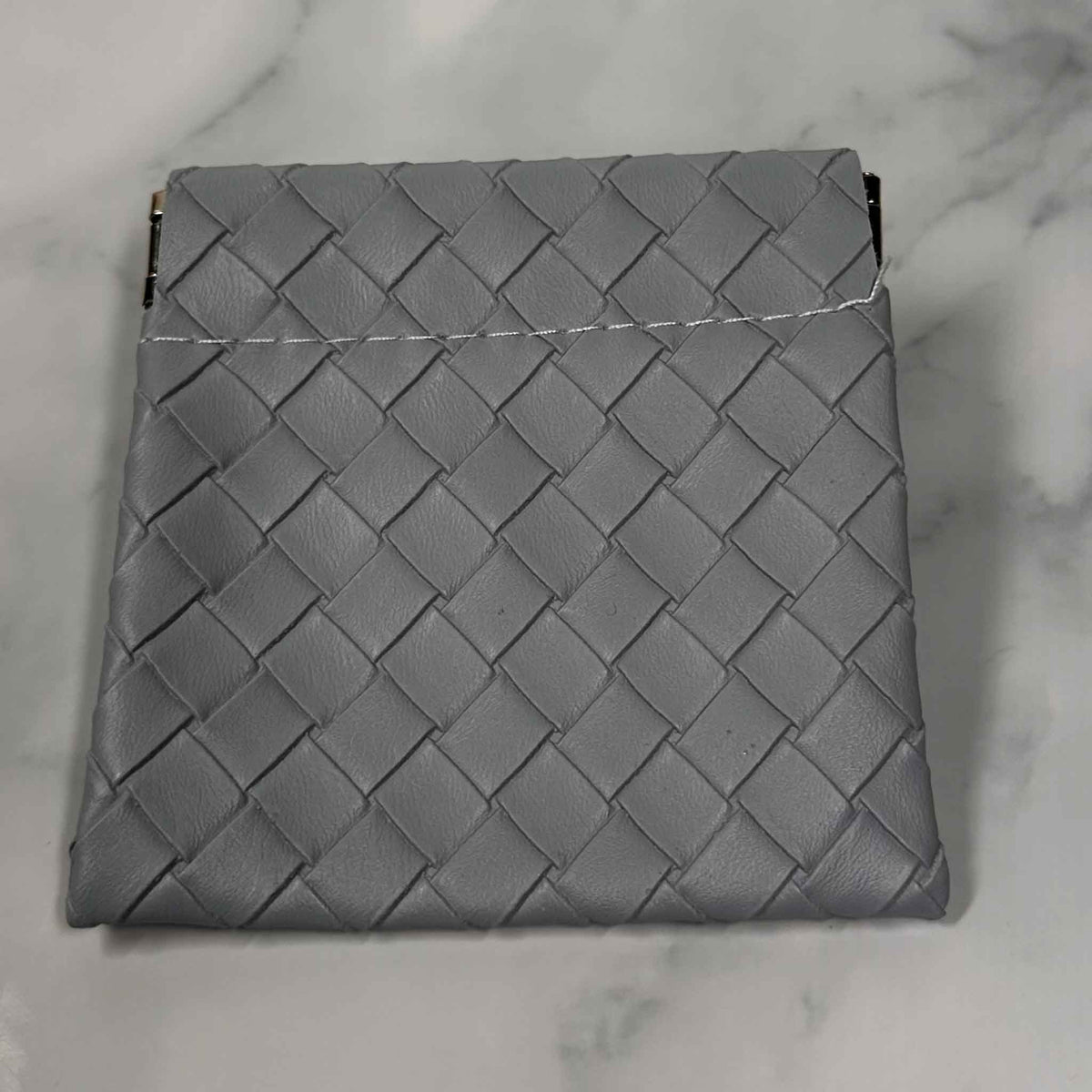 Gray woven Showalux personal bag on a marble surface