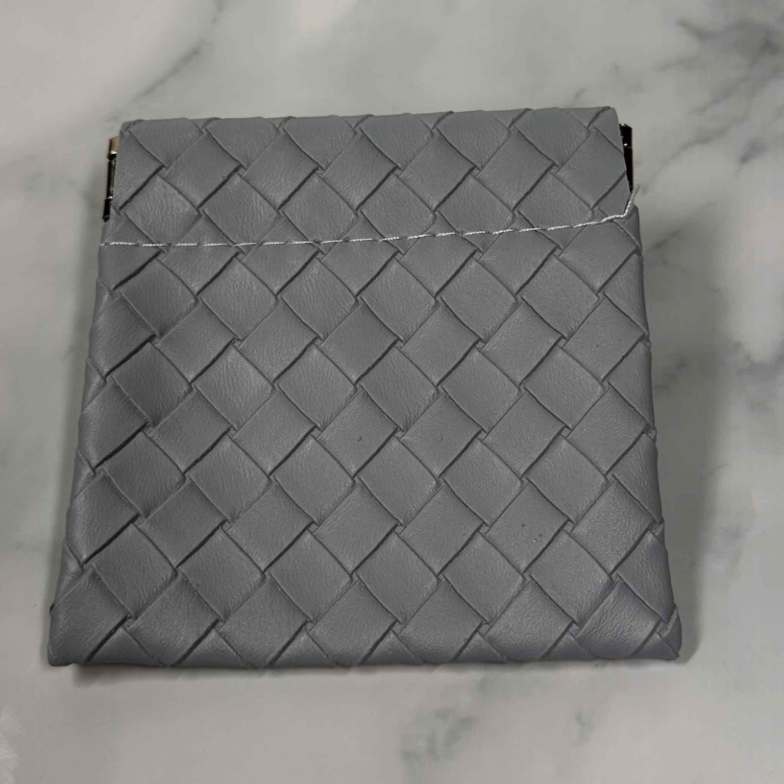 Gray woven Showalux personal bag on a marble surface