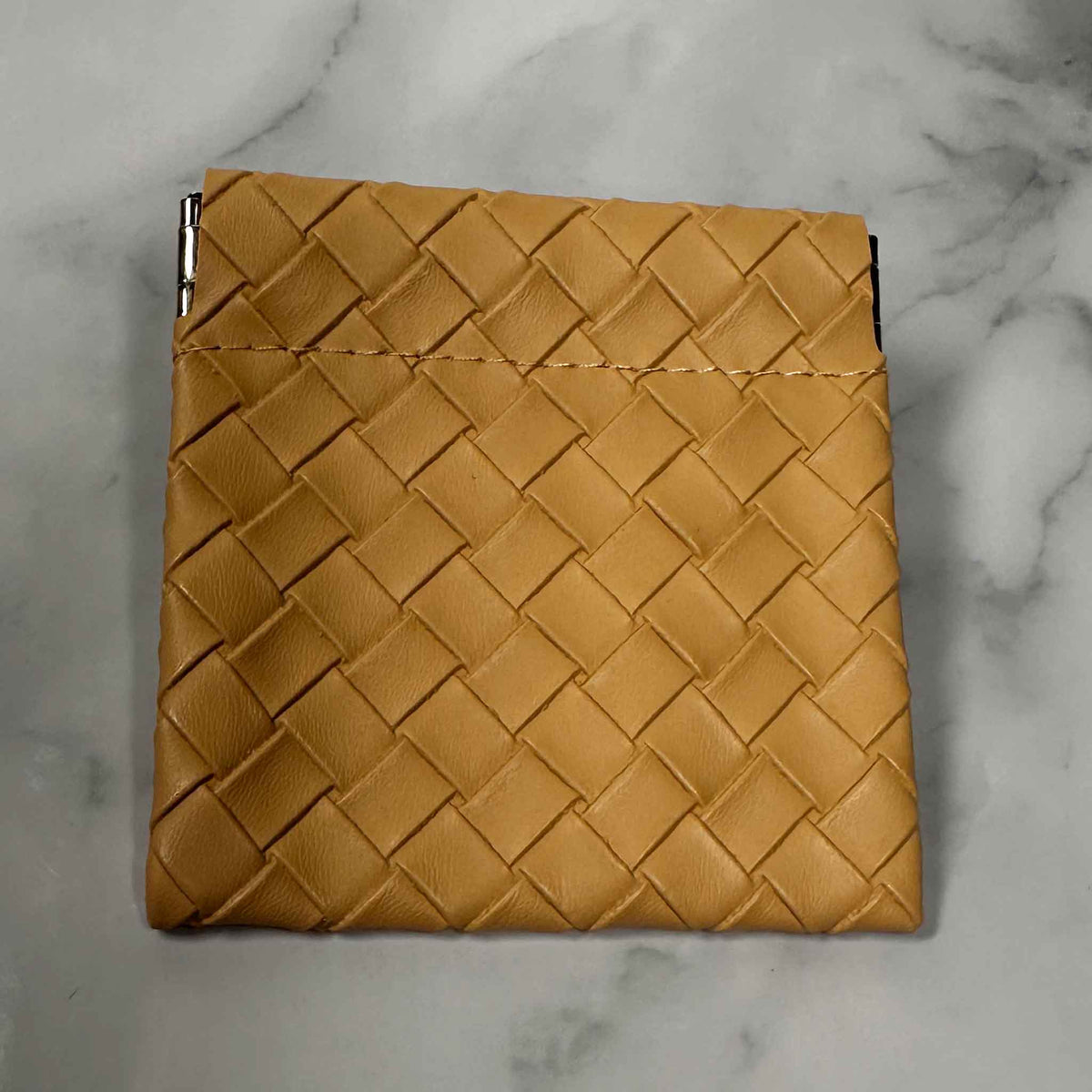 Tan Showalux woven pouch on a marble surface