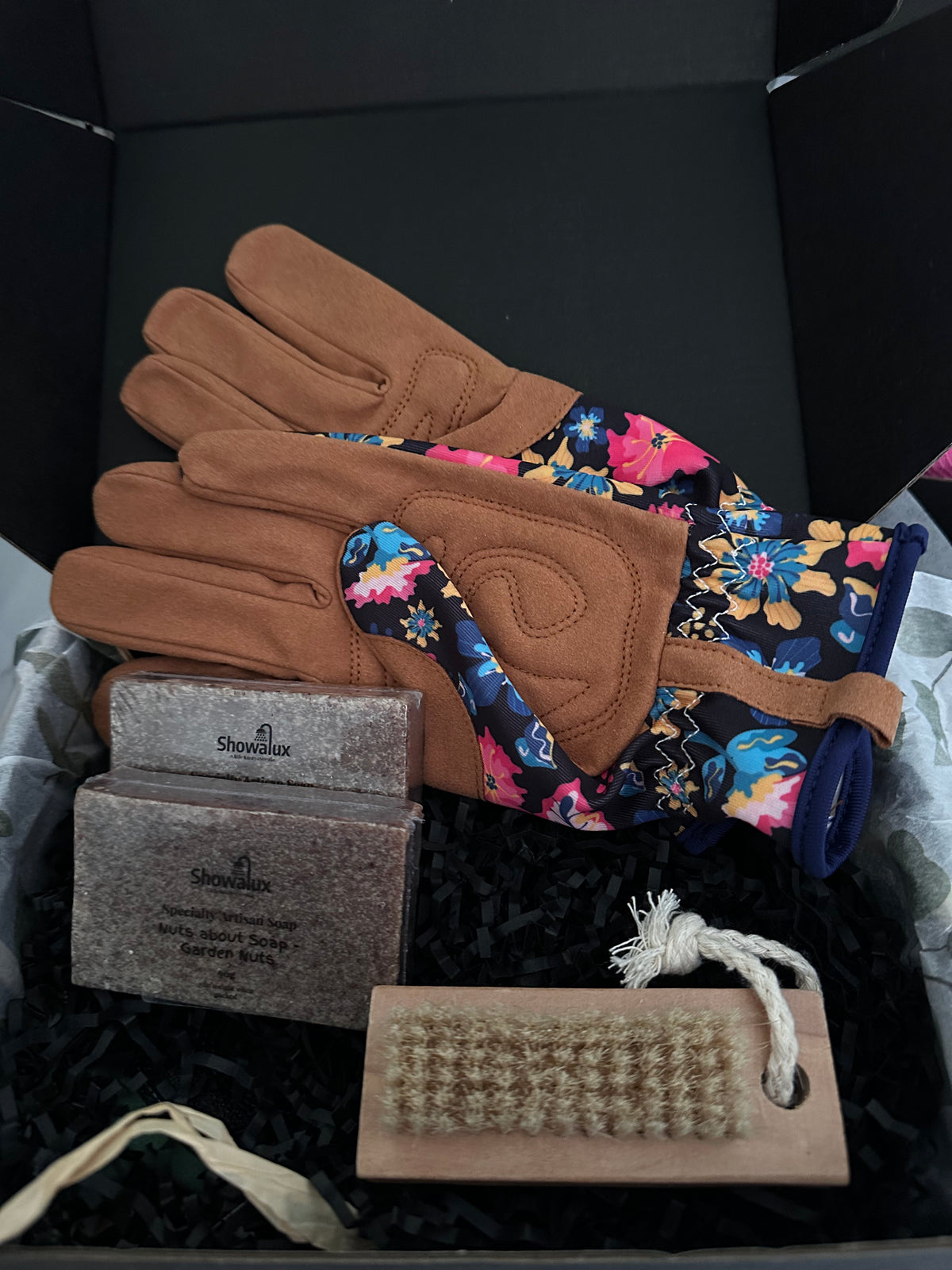 Pair of brown gloves with floral pattern on a black surface