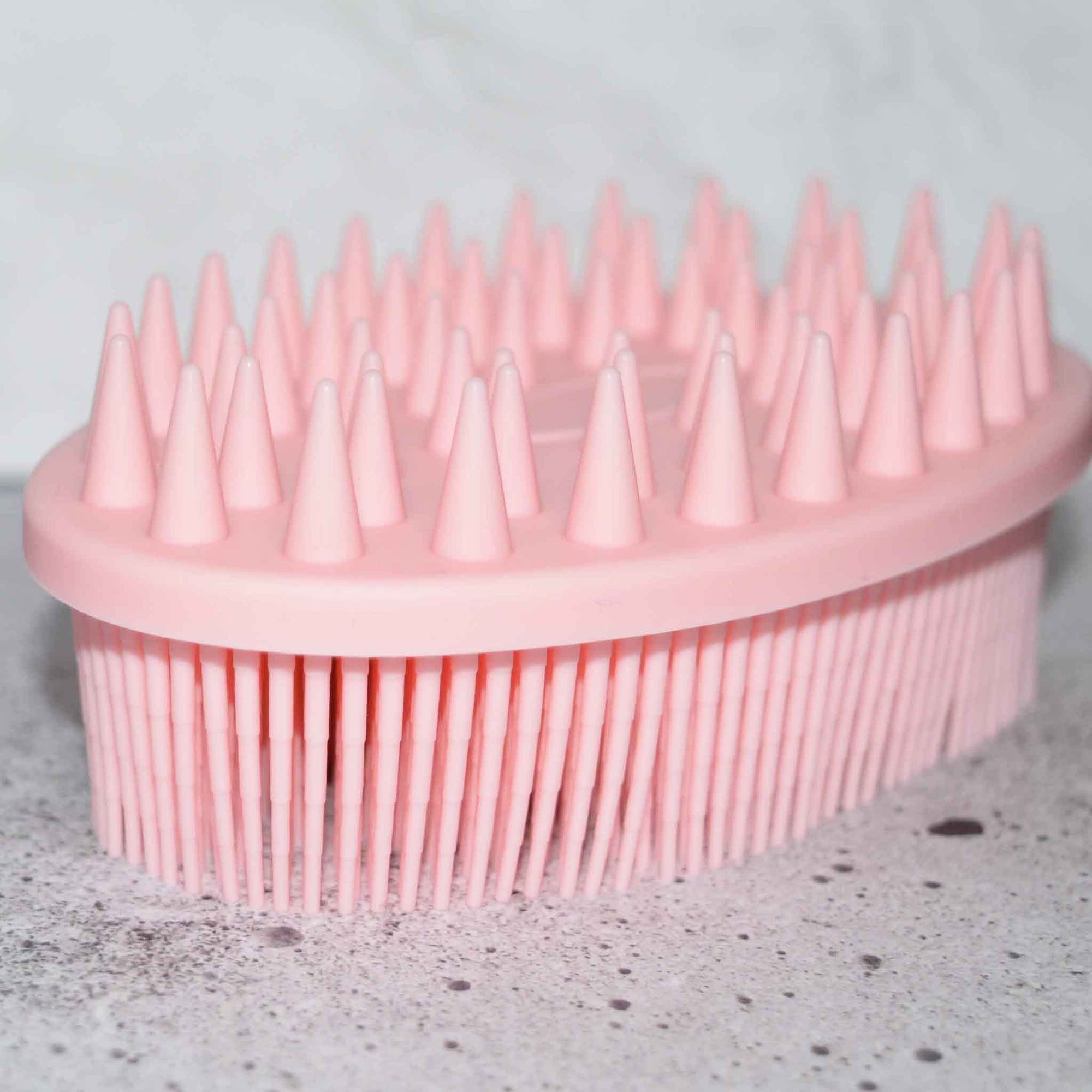 Pink soft silicone scrub brush with very soft fine bristles on one side, and short firm nubs on the other side