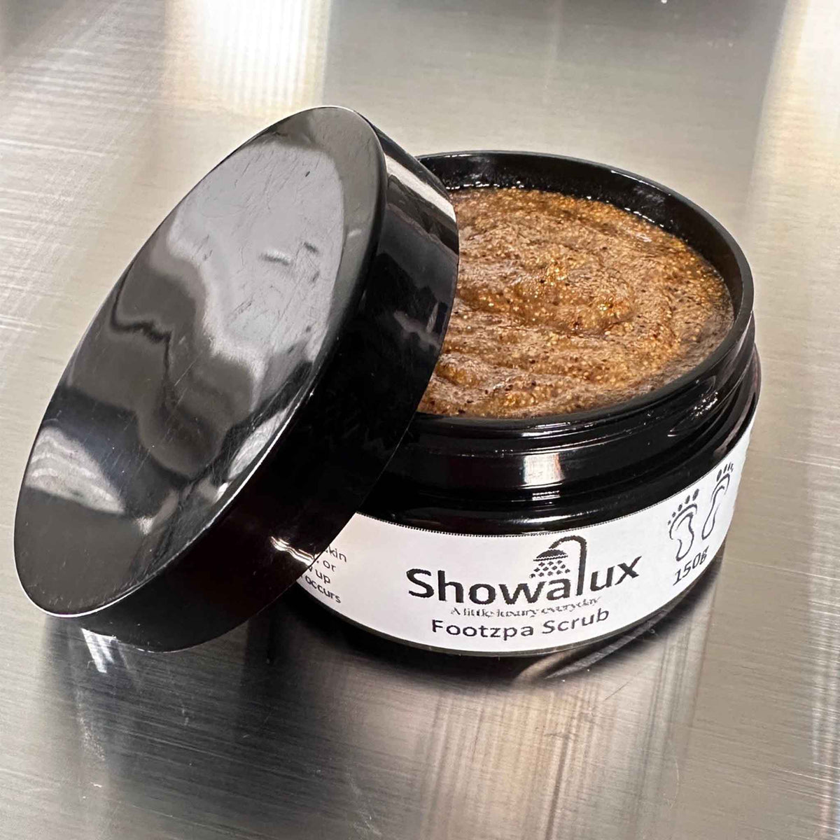 Showalux Footzpa Scrub in a black container on a metallic surface