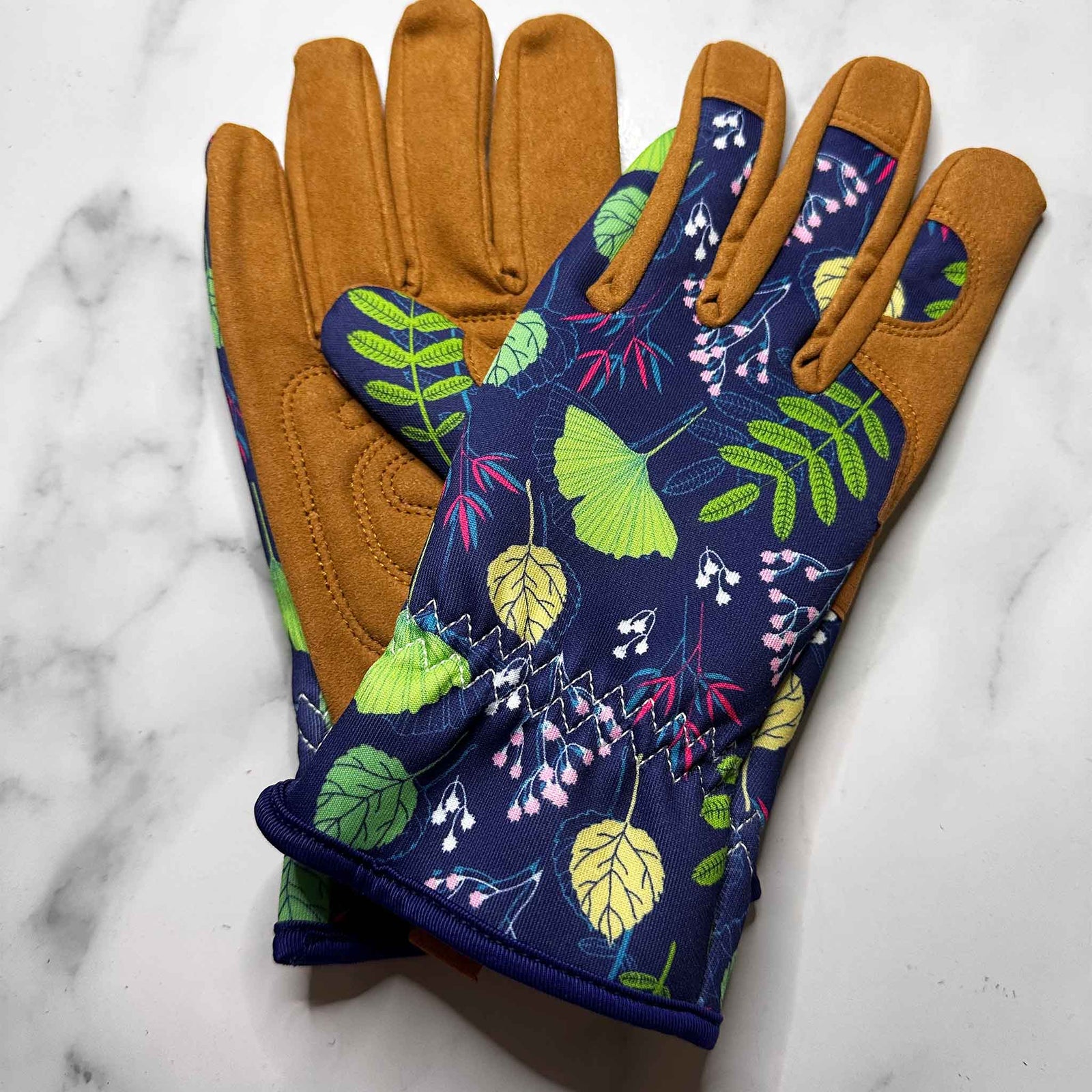 Pair of gardening gloves with floral pattern on a marble surface