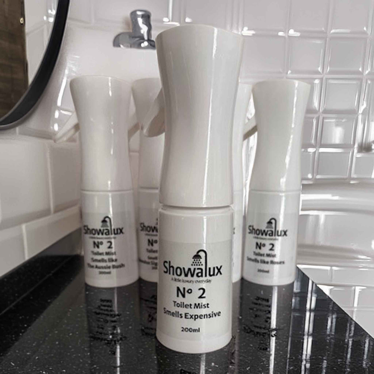 Showalux toilet mist in "Smells Expensive" on a bathroom counter with tiled wall in the background