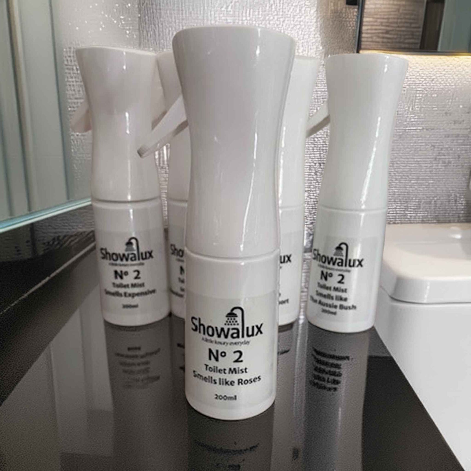 Showalux toilet mist in "Smells like Roses" on a bathroom counter with tiled wall in the background