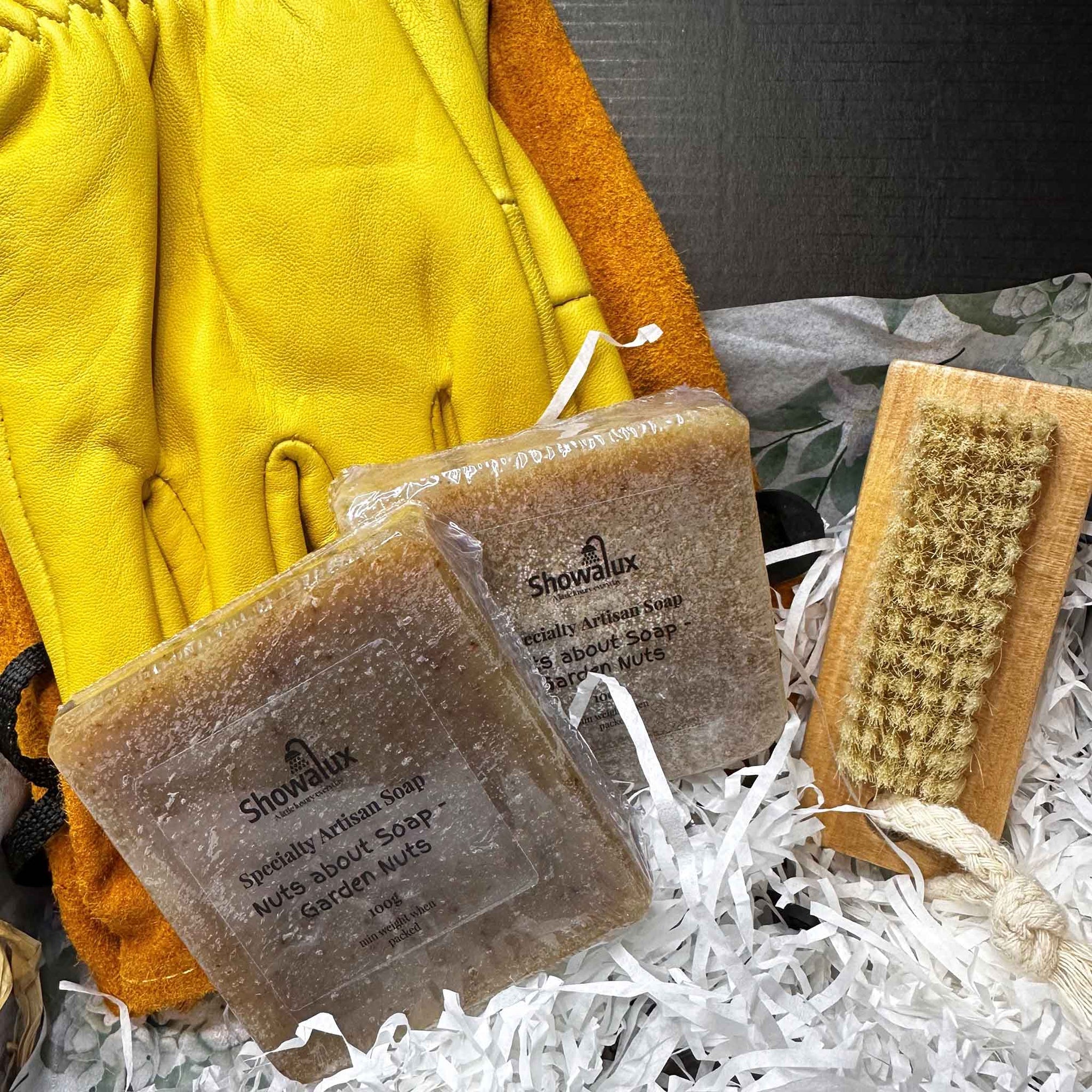 Showalux soap bars with a brush and yellow gloves on white shredded paper